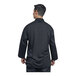 A man wearing a black Uncommon Chef Treviso chef coat with black mesh back.