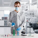 A man wearing a Lavex white lab coat and gloves holding a test tube.