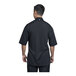 A man wearing a Uncommon Chef black short sleeve chef coat with a black mesh back.