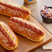 Three Sabrett beef hot dogs with mustard on a cutting board with coleslaw.