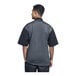 A man wearing a black Uncommon Chef Brac chef coat with silver heather mesh on the back.