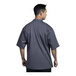 A man wearing a Uncommon Chef Luca short sleeve chef coat with a slate grey front and mesh back.