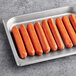 A tray of Sabrett skinless spicy beef hot dogs on a gray surface.