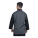 A man wearing a Uncommon Chef black 3/4 sleeve chef coat with a silver heather mesh back.
