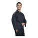 A man wearing a Uncommon Chef black chef coat with silver mesh on the back.