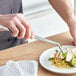 A person using Mercer Culinary curved tongs to plate food.
