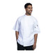 A man in a white Uncommon Chef Luca short sleeve chef coat with white mesh back.