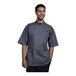 A man wearing a Uncommon Chef slate and gray chef coat with a mesh back smiling.