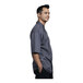 A man wearing a Uncommon Chef slate grey short sleeve chef coat with a mesh back.
