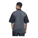 A man wearing a black Uncommon Chef Brac short sleeve chef coat with silver heather mesh on the back.