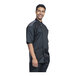 A man wearing a black Uncommon Chef Brac short sleeve chef coat with silver mesh.