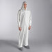 A man wearing a white Lavex coverall with attached hood, boots, and elastic wrists.