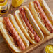 Three Vienna Beef Ditka hot dogs on buns with mustard and onions on a table in a stadium concession stand.