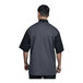 A man wearing a black and grey Uncommon Chef Modena chef coat with silver heather mesh on the back.