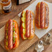 Three Vienna Beef skinless hot dogs with jalapenos and cheddar cheese on a cutting board.