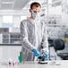 A person wearing Lavex White Polypropylene Coveralls, a face mask, and gloves.