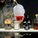 A person using a Flavour Blaster Gold magnetic nozzle to add smoke to a glass of liquid.