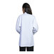 A woman wearing a Uncommon Chef white long sleeve chef coat with white mesh back.