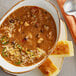 A bowl of Vienna Beef Sweet Heat Turkey Chili with a spoon and cornbread on a plate.