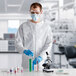 A man wearing a white Lavex coverall suit and gloves holding test tubes.