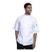 A man in a white Uncommon Chef Luca chef coat with white mesh back smiling.
