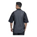 A man wearing a black Uncommon Chef short sleeve chef coat with a grey mesh back.