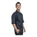 A man wearing a Uncommon Chef black short sleeve chef coat with silver mesh on the back.