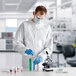 A man wearing a white Lavex lab coat and goggles holding a test tube.