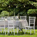 A table set with a Lancaster Table & Seating White Wood Chiavari Chair and a white tablecloth.