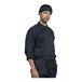 A man wearing an Uncommon Chef black long sleeve chef coat with a black mesh back.