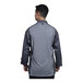 A man wearing a Uncommon Chef slate grey long sleeve chef coat with a grey mesh back.