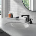 A bathroom sink with a mirror and a Delta Ashlyn matte black deck-mount faucet with metal pop-up drain and lever handles.