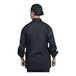 A man wearing a black Uncommon Chef Pisa long sleeve chef coat with black mesh back.