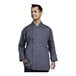 A man wearing a Uncommon Chef slate grey long sleeve chef coat with a grey mesh back.