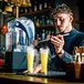 A man uses a Flavour Blaster JetChill to add smoke to a yellow cocktail.