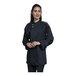 A woman wearing a black Uncommon Chef long sleeve chef coat with silver mesh on the back.