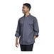 A man wearing a Uncommon Chef Pescara slate long sleeve chef coat with a grey shirt underneath.