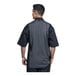 A man wearing a black Uncommon Chef short sleeve chef coat with silver heather mesh.