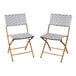 A pair of navy and white synthetic rattan folding chairs with natural steel frames.