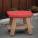 A red Mayne Mesa side table on a concrete patio.