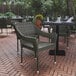 A Flash Furniture Ethan Gray synthetic rattan arm chair on a table with plates and napkins outside.