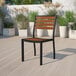 A Flash Furniture Lark natural faux teak slat stackable side chair on an outdoor patio with potted plants.