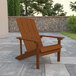 A brown wooden Flash Furniture Charlestown Adirondack chair on a stone patio.