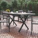 A Flash Furniture rectangular faux teak table with gray metal X-frame on a brick patio.