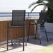 Two Flash Furniture black stackable barstools with metal frames on an outdoor patio.