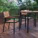 A Flash Furniture Lark natural faux teak slat arm chair on a deck with a table and chairs.