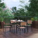 A Flash Furniture square table with faux teak slats and four stackable arm chairs on a deck.