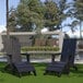 Two Flash Furniture black Adirondack chairs on grass next to a pool.
