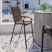 A brown Flash Furniture Brazos stackable barstool on an outdoor patio.