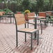 A Flash Furniture Finch natural faux teak slat side chair on a brick patio table.